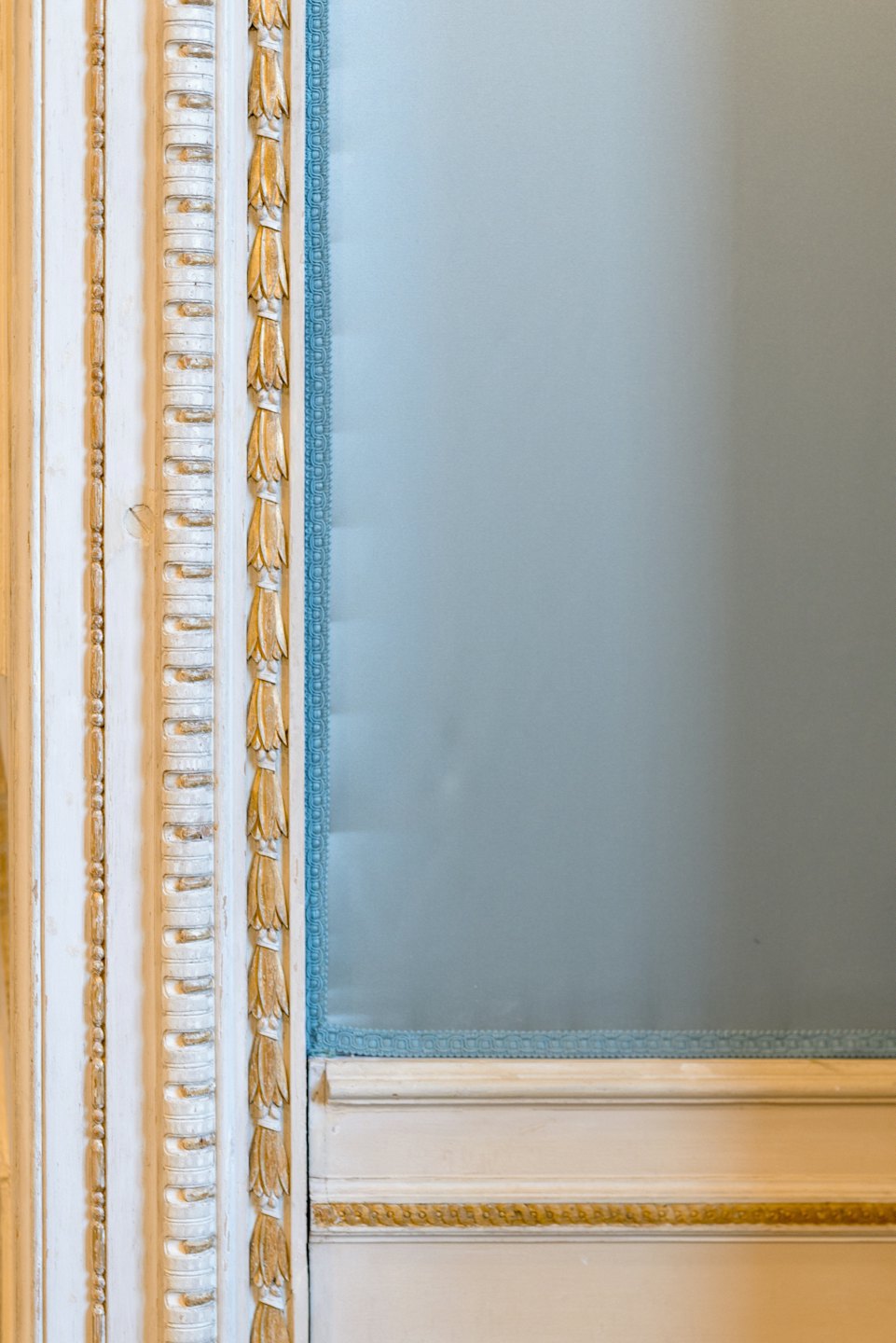 Weiße Zierleisten mit goldenen Akzenten neben einer blauen Verkleidung mit Zierleisten.