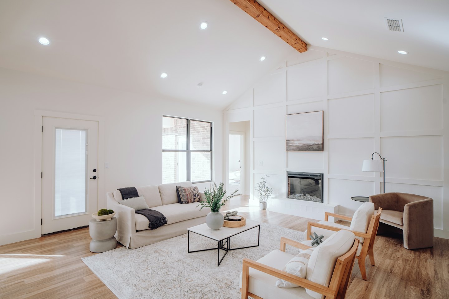 Modernes Wohnzimmer mit cremefarbener Couch und Akzentstühlen aus Holz.
